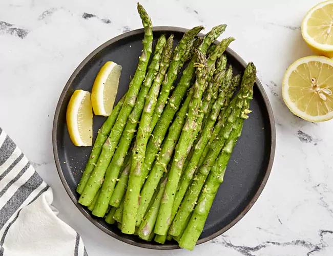 asparagus vegetable with lemon fruit pieces in plate